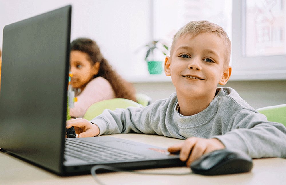 A young boy smiling while learning to read with Reading Kingdom